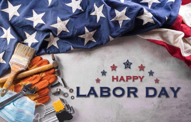 istock Happy Labor day concept during coronavirus disease (Covid-19). American flag with different construction tools and medical mask on dark stone background. 1416912310