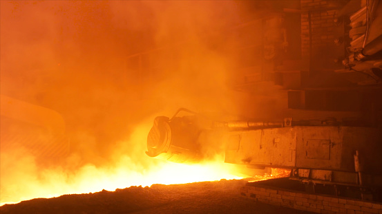 Hot steel production at the steel plant, metallurgy concept. Hot shop with flowing molten steel in the chute.