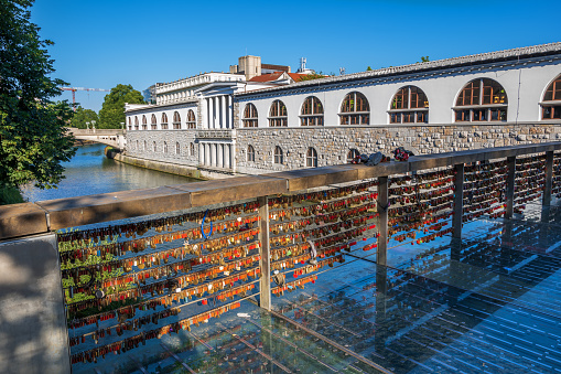 Ljubljana, Slovenia - July 13, 2022: Love padlocks on the Butchers Bridge (Slovene: Mesarski most) on river Ljubljanica and Plecnik Arcades, city landmarks