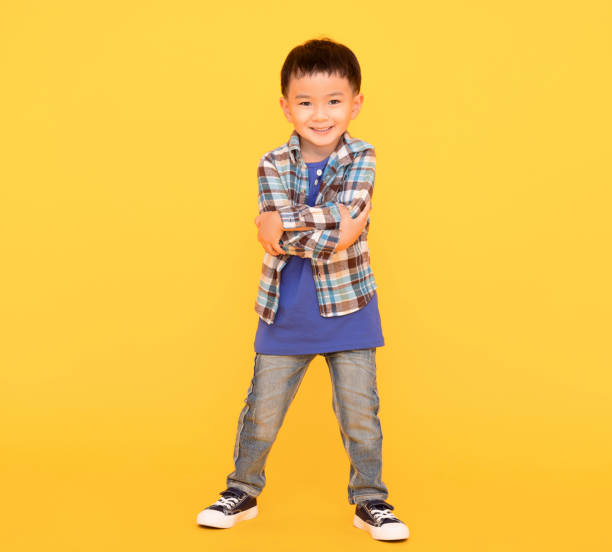 istock happy asian kid standing  over yellow background 1416925971