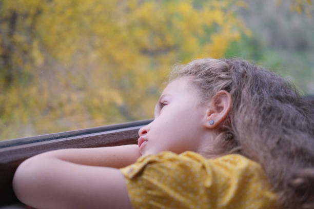istock cute little girl looking out the window. 1416931283