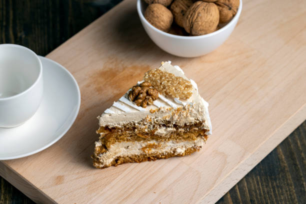 a piece of cake with buttercream and walnuts, a sweet and delicious dessert with walnuts on the board