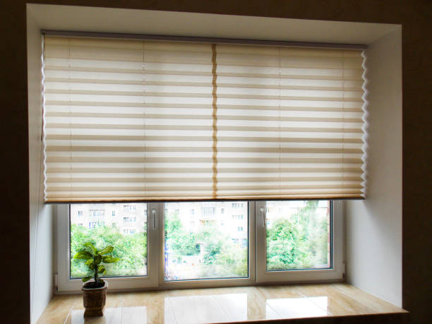Pleated blinds XL close uo on the window Pleated blinds XL, beige color, with 50mm fold closeup in the window opening in the interior. Home blinds - modern bottom up privacy shades half raised on apartment windows. honeycomb pattern photos stock pictures, royalty-free photos & images