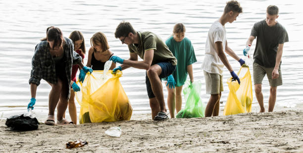 a team of teenagers collect garbage on the river bank stock photo