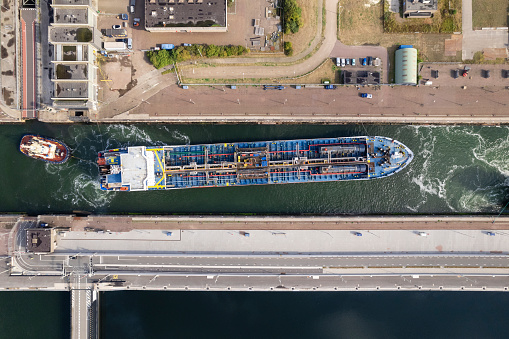 Aerial color image of a ship carrying liquefied natural gas entering the lock in IJmuiden with tugboat the Netherlands.