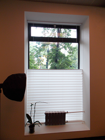 Pleated blinds XL, white color, with 50mm fold closeup in the window opening in the interior. Home blinds - modern top down bottom up privacy shades on apartment windows.