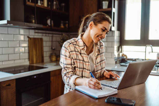 istock Smiling woman is using laptop and writing notes 1416941542
