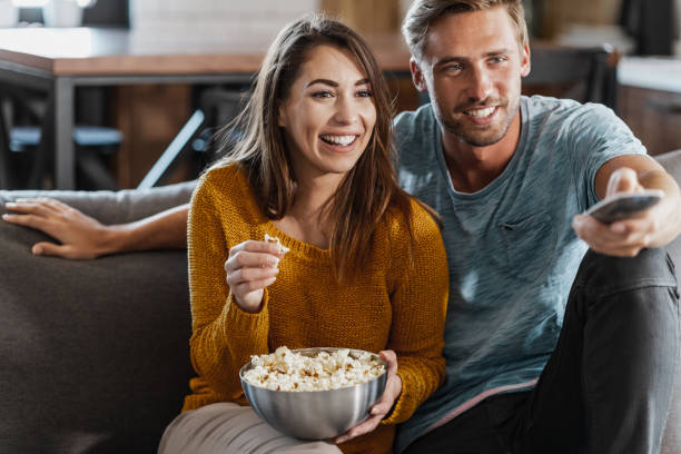 istock Cheerful couple smiling while watching TV show 1416942583