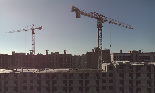 Construction of a new residential area. Multi-storey building under construction. Cranes in the frame. Themes of housing and real estate