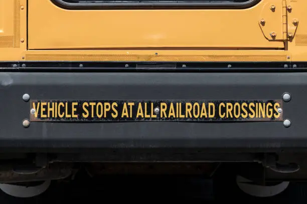 Vehicle Stops at All Railroad Crossings sign on the back of a School Bus.