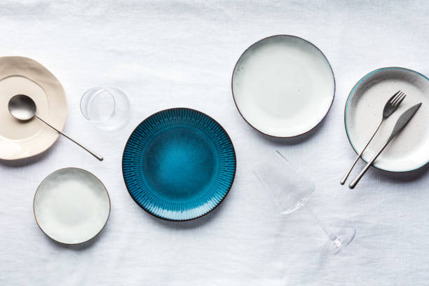 set di stoviglie moderne con posate, bicchieri e un vibrante piatto blu - plate blue dishware white foto e immagini stock