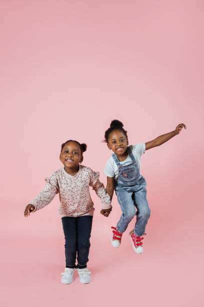 istock Pleased little girlfriends holding hands and jumping together. 1416943806