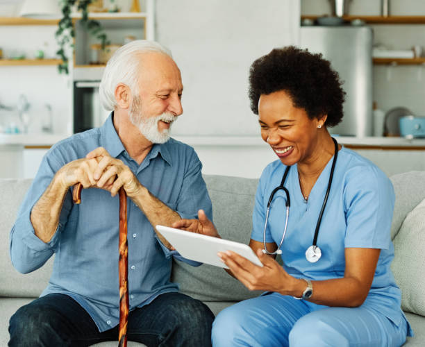 istock nurse doctor senior care tablet computer technology showing caregiver help assistence retirement home nursing elderly woman african american black happy laughing man 1416947141