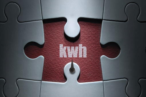 Missing piece from a jigsaw puzzle with dial pointing to kwh; energy usage concept