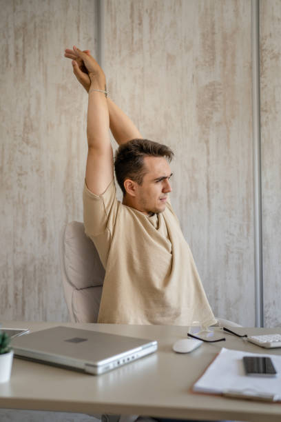 istock young man stretching at work while sitting at desk having back pain 1416953833