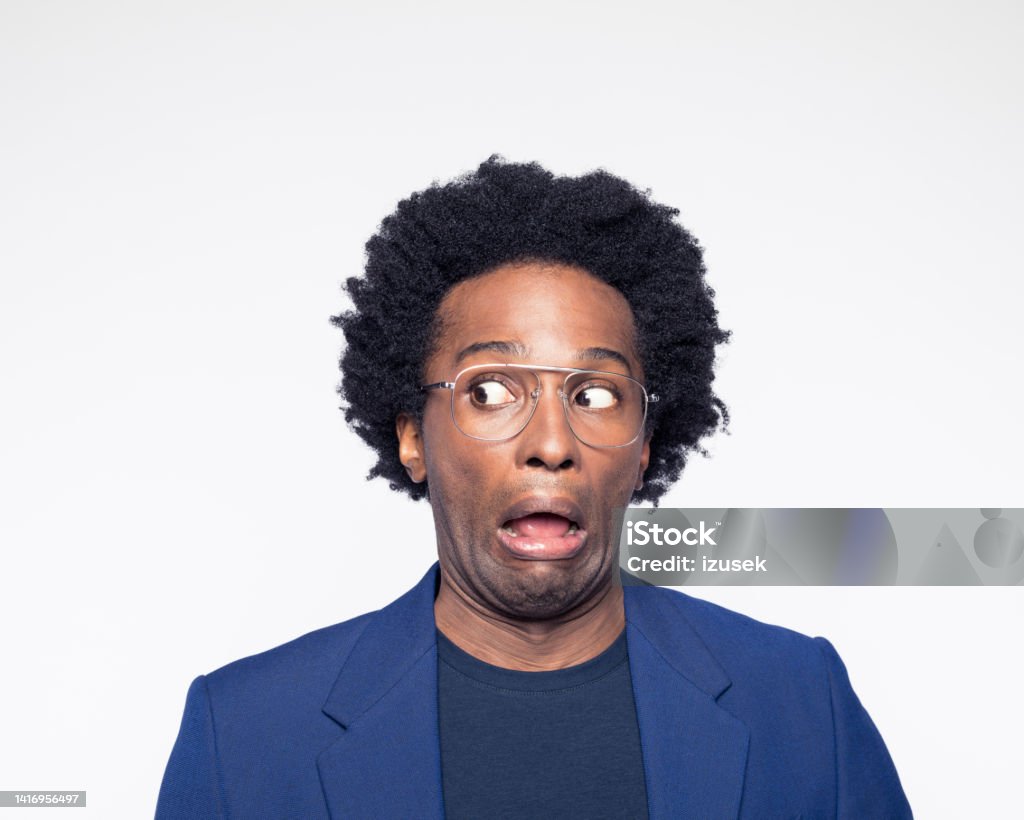 Disappointed man looking away Headshot of confused man wearing navy blue suit jacket looking away with mouth open. Studio shot against white background. Business Person Stock Photo