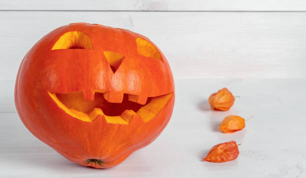 istock Jack lantern carved from ripe pumpkin on a light wooden background. 1416957379