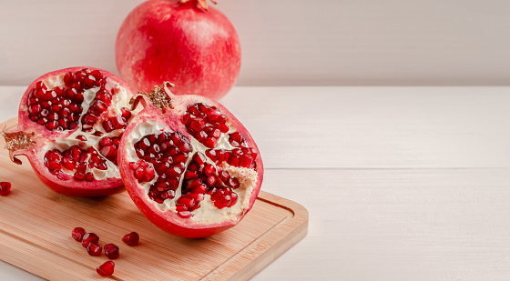 Two halves of a ripe pomegranate on a wooden board. Copy space.Selective focus.