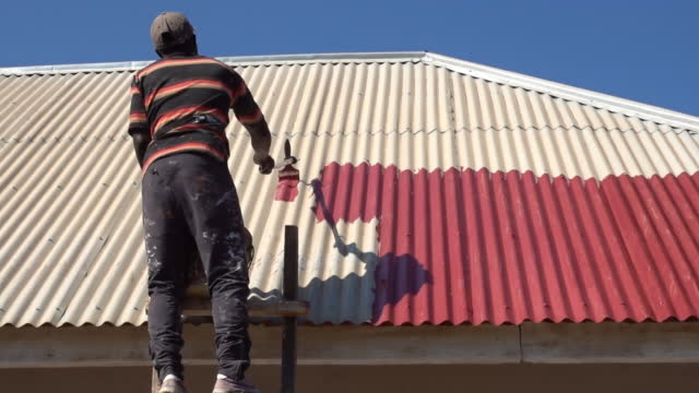 African man painting the rooftop