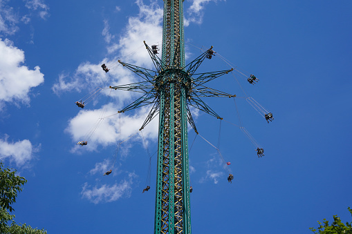 People enjoying the swing ride in amusement park against blue sky