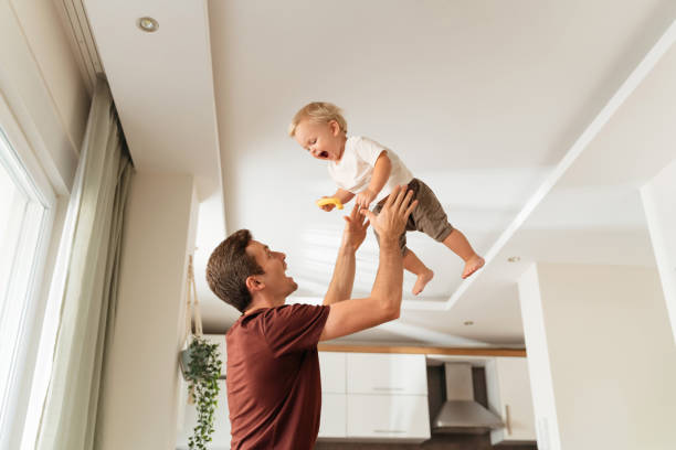 istock Dad throwing excited laughing baby boy up in air and catching after returning home from work 1416966301