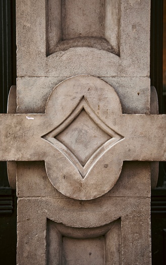 Close-up of an architectural detail of a design molded in cement on a column of a city building