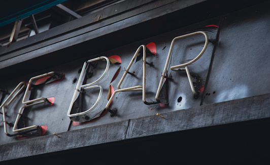 Detail of a neon bar sign turned off during the daytime indicating the bar is closed