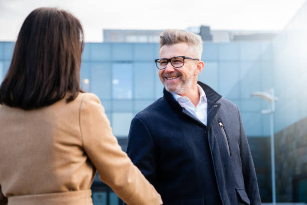 istock Business man shaking hands with his female partner celebrating successful teamwork, standing in front of his office's building 1416968637