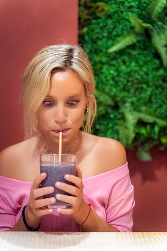 Woman enjoying drinking a fresh healthy smoothie in a coffee shop. Healthy lifestyle and beverages concept.