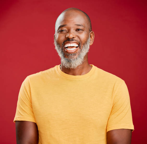 istock Mature african american man with a beard standing and smiling against a red studio background. Happy, positive, carefree. Laughing, cheerful, joy 1416970332