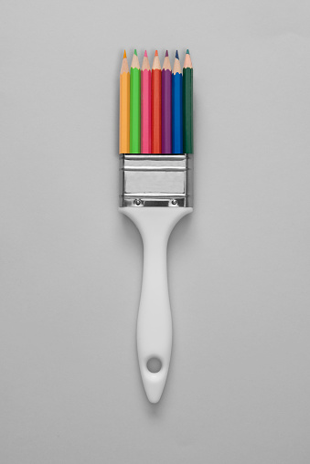 Pencil paintbrush over colored background, directly above.