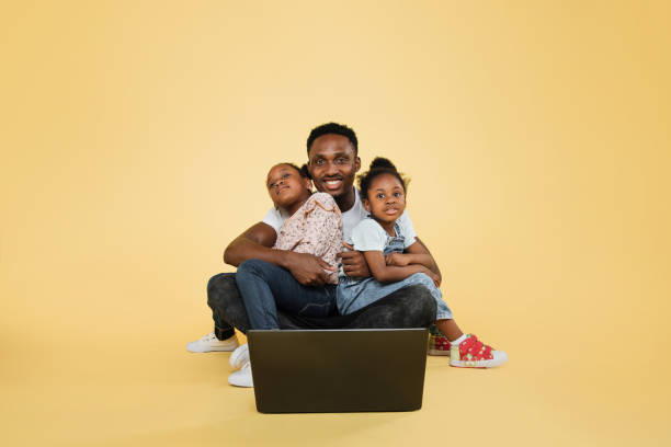 istock Happy african american daddy and his two little cute daughters spending time together using laptop 1416974643
