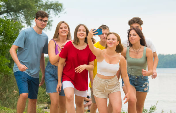 a group of teenagers take a fun selfie on vacation in nature using a smartphone stock photo