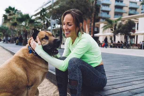istock Smiling young women hugging with dog on street 1416993021