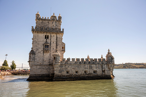 May 27, 2022, Lisbon, Portugal: A view of Belém Tower on the banks of the Tagus River being visited by tourists.  Belém Tower, officially the Tower of Saint Vincent is a 16th-century fortification located in Lisbon that served as a point of embarkation and disembarkation for Portuguese explorers and as a ceremonial gateway to Lisbon.