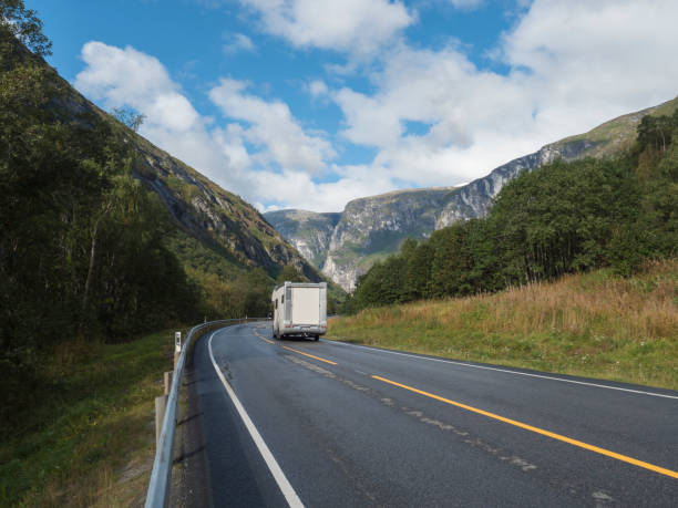 istock White camper van car at Winding road E136 with mountain massif Trolltindene, Troll wall Trollveggen in Romsdal valley, Norway. Blue sky white clouds. Summer road trip travel scenery. 1417007181