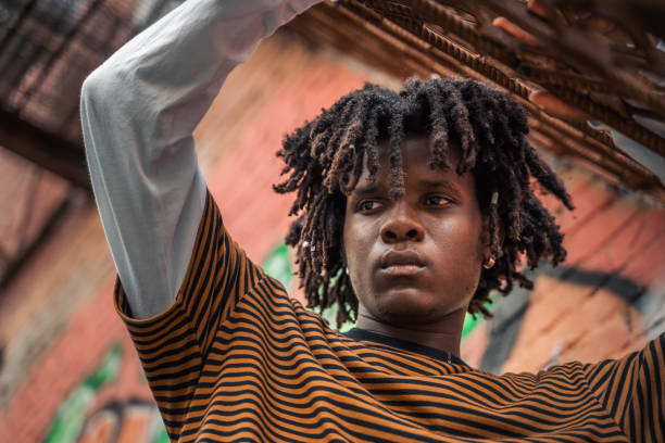 porträt eines jungen, gutaussehenden, stilvollen schwarzen mannes mit natürlichen haardreadlocks. afroamerikanischer typ. treppe, mit graffiti bemalte wand im armen viertel des stadtviertels street art culture. afroamerikaner skateboarder mann. millennia - graffiti men wall street art stock-fotos und bilder