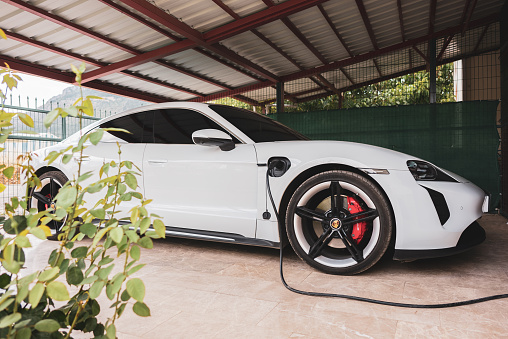Antalya,Turkey : August 21,2022 View of parked electric Porsche car connected to the charging station in the garden garage.