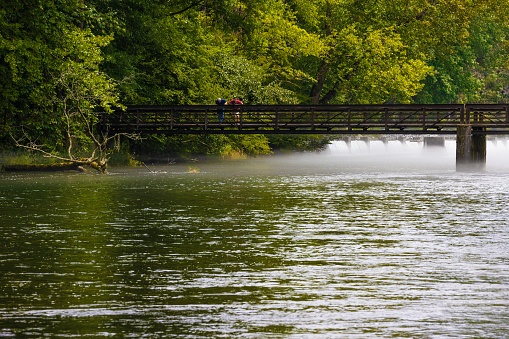 Two men standing on bridge crossing the South Holston River,  as summer fog dissipates.