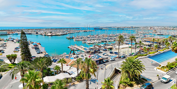 Panoramic photo Torrevieja puerto seaport view from above, scenic palm-tree lined seafront, nautical vessels moored on Mediterranean Sea bay. Costa Blanca. Province of Alicante. Spain. Travel concept