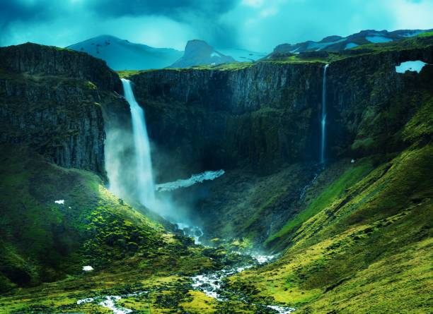 istock Splendid view of a waterfall splashing down from a cliff in a valley under a gloomy sky 1417022135