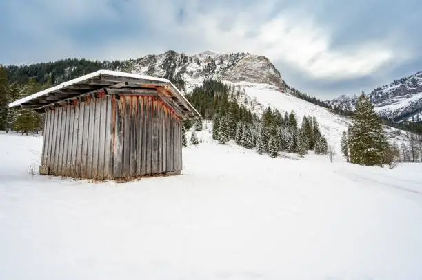 An old wooden hut on a snowy slope of Alpen mountains