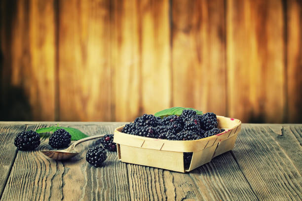 Blackberries in a basket on a wooden rustic table on a wooden background