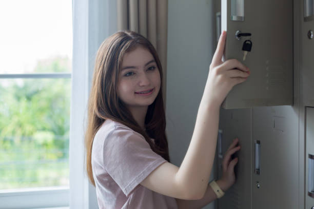 istock student opening her locker at the school. A Girl student smiles while opening her locker. 1417032811