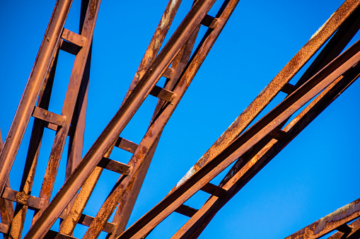 Close-up image of rusting steel machinery against a clear blue sky