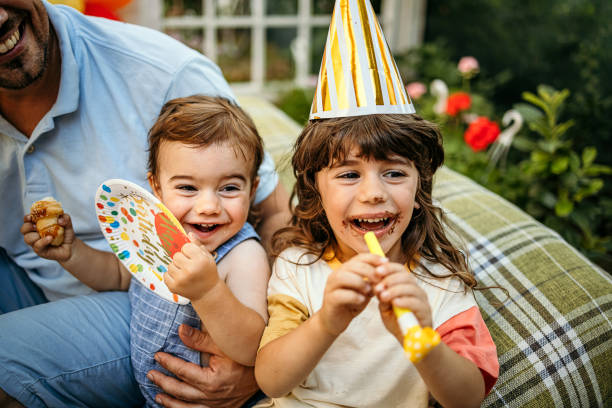 Sly boy in birthday cap going to burst balloon of his brother
