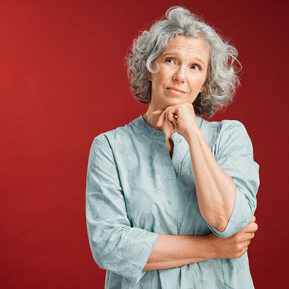 Mature woman thinking, making a decision or choice about what to wear with copy space. Confused senior caucasian female lost in her thoughts. Serious and uncertain retired lady choosing an option.