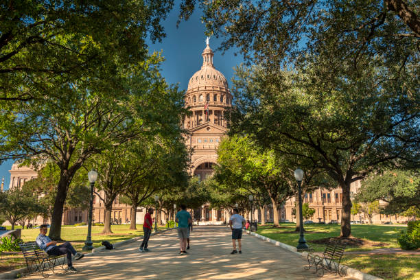 Austin, Texas, USA - November 15, 2021:  People wolk by the Texas State Capitol building as seen down the streets of Congress Avenue.  Austin is the state capital of Texas