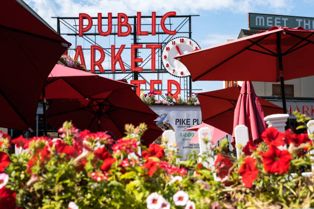 Pike Place Market Seattle, USA - Aug 12th 2022: The iconic Public Market sign at Pike Place Market mid day with flowers in the foreground. pike place market stock pictures, royalty-free photos & images