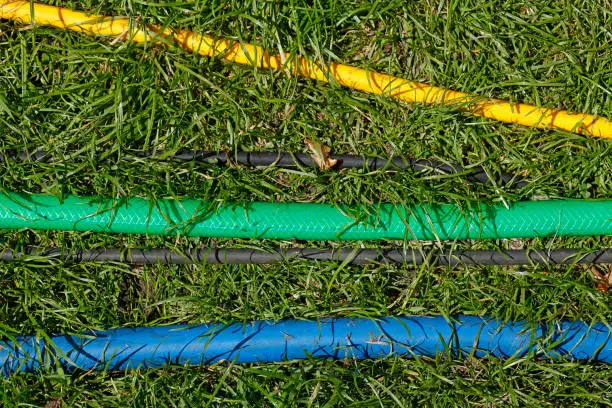 Colorful garden hoses lying on a lawn, Germany